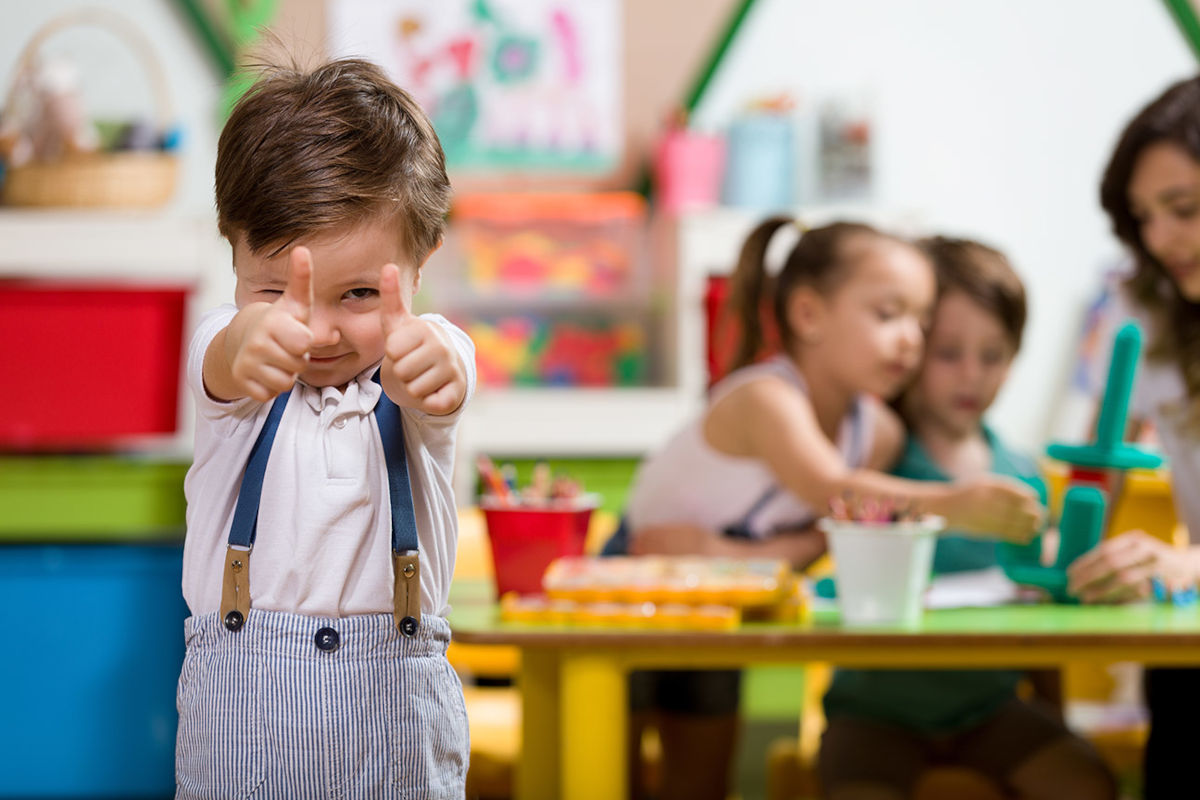 Un niño muestra pulgares arriba en la escuela infantil