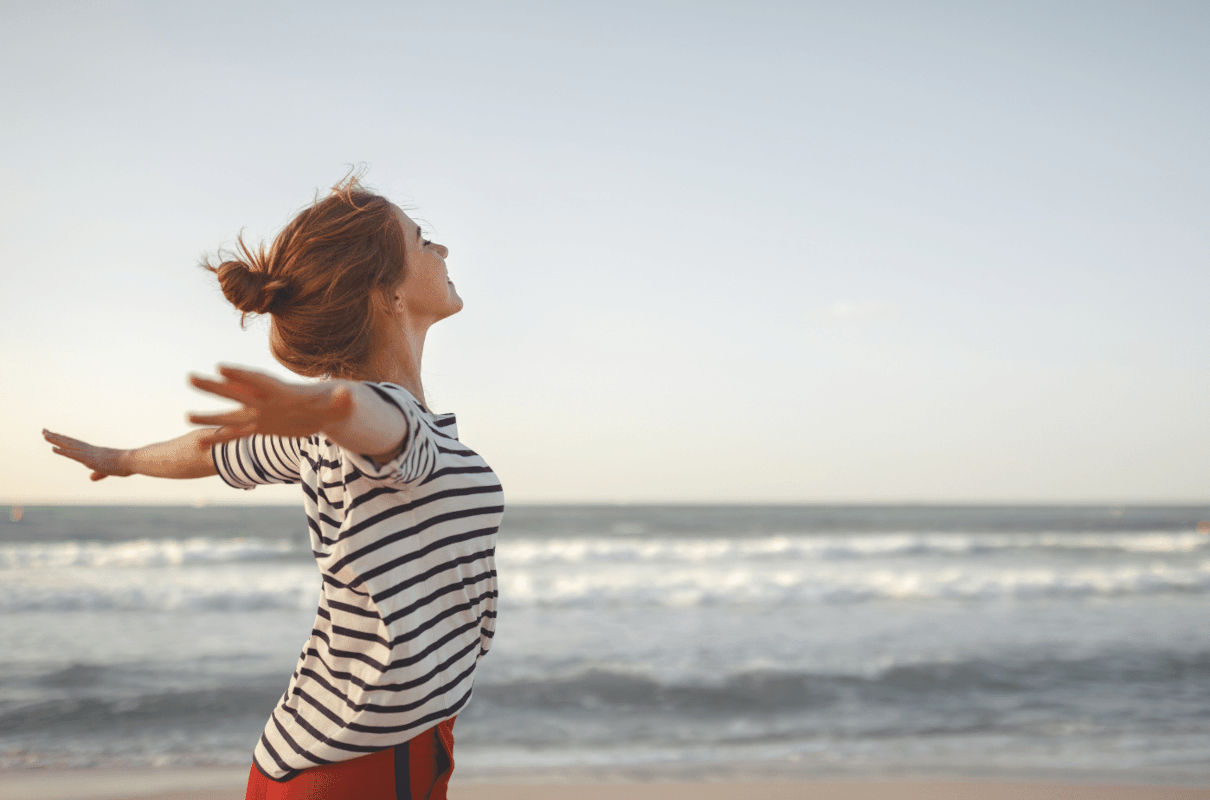 Una chica extiende los brazos mirando al mar