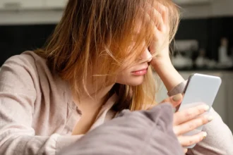 Mujer decaída mirando teléfono.