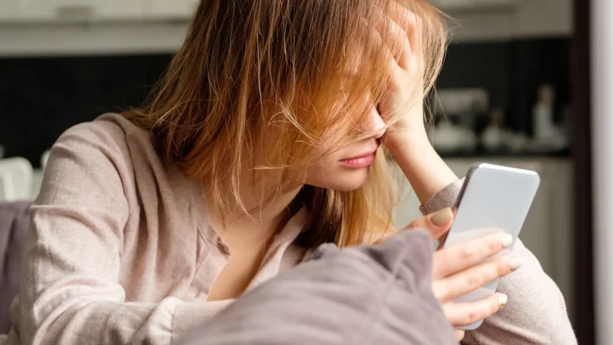 Mujer decaída mirando teléfono.
